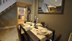 A dining area with a table set for four, a mirror on the wall, and a staircase in the background. - 54 On the Rocks- characterful coastal cottage (Anstruther)