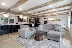 Relax in this open-plan living space featuring a kitchen area with a bar, sofa, and armchairs.
