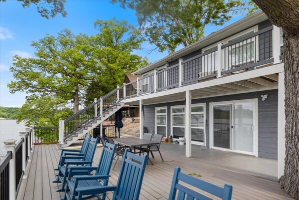 Una terraza con mobiliario exterior y una escalera que conduce a un segundo piso con balcón.