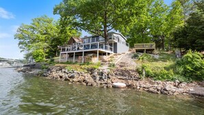 A lakeside property with a large house, a dock, and a stone pathway leading to the water.