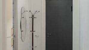 A hallway with a coat rack, a dark door, and a patterned rug. - Prime City Residence by Sweet Home (Yerevan)