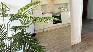 Una cocina moderna con armarios blancos, horno integrado y microondas.