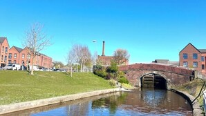 A canal with a bridge, buildings, and a chimney.
