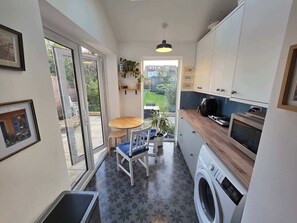 A compact kitchen with a washing machine, a microwave, and a dining area with a table and chairs.