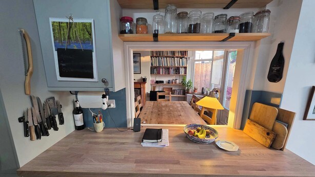 A kitchen with a wooden countertop, a dining table, and a bookshelf filled with books. - Peaceful 3BDR Retreat by Epping Forest Chingford (Greater London)