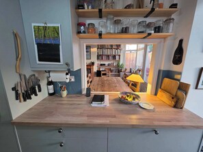 A kitchen with a wooden countertop, a dining table, and a bookshelf filled with books.