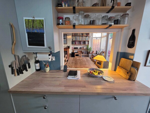 A kitchen with a wooden countertop, a dining table, and a bookshelf filled with books.