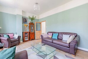 A living room with a glass coffee table, two sofas, a cabinet, and a door.