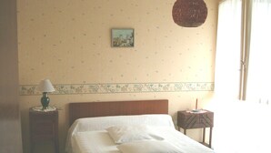 Ein Schlafzimmer mit einem hölzernen Bett, einem Nachttisch mit Lampe, einem kleinen Tisch mit Kerze und einem Bild an der Wand.