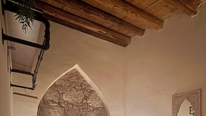 Une chambre à coucher avec un lit, deux lampes de chevet, un mur en pierre décoratif et un luminaire suspendu.