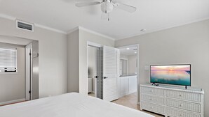 Ein Schlafzimmer mit Bett, Kommode, Fernseher und Deckenventilator.