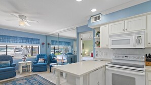 A modern kitchen with white cabinetry, a built-in microwave, and a large island.