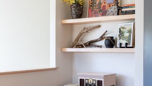 A modern living room with a wooden bench, a brown leather couch, and a bookshelf with decorative items and books.