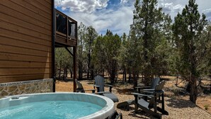 A hot tub with chairs, surrounded by trees and a wooden deck.
