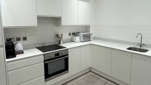 A modern kitchen with white cabinets, a black stove, a microwave, and a sink.