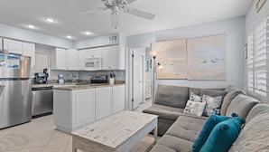 A modern kitchen with white cabinets, a central island, and a ceiling fan. - ☀️BEACH FRONT-Capri by the Gulf 120 (Destin)