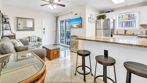 A modern kitchen with a large island, a ceiling fan, and a view to the outside.