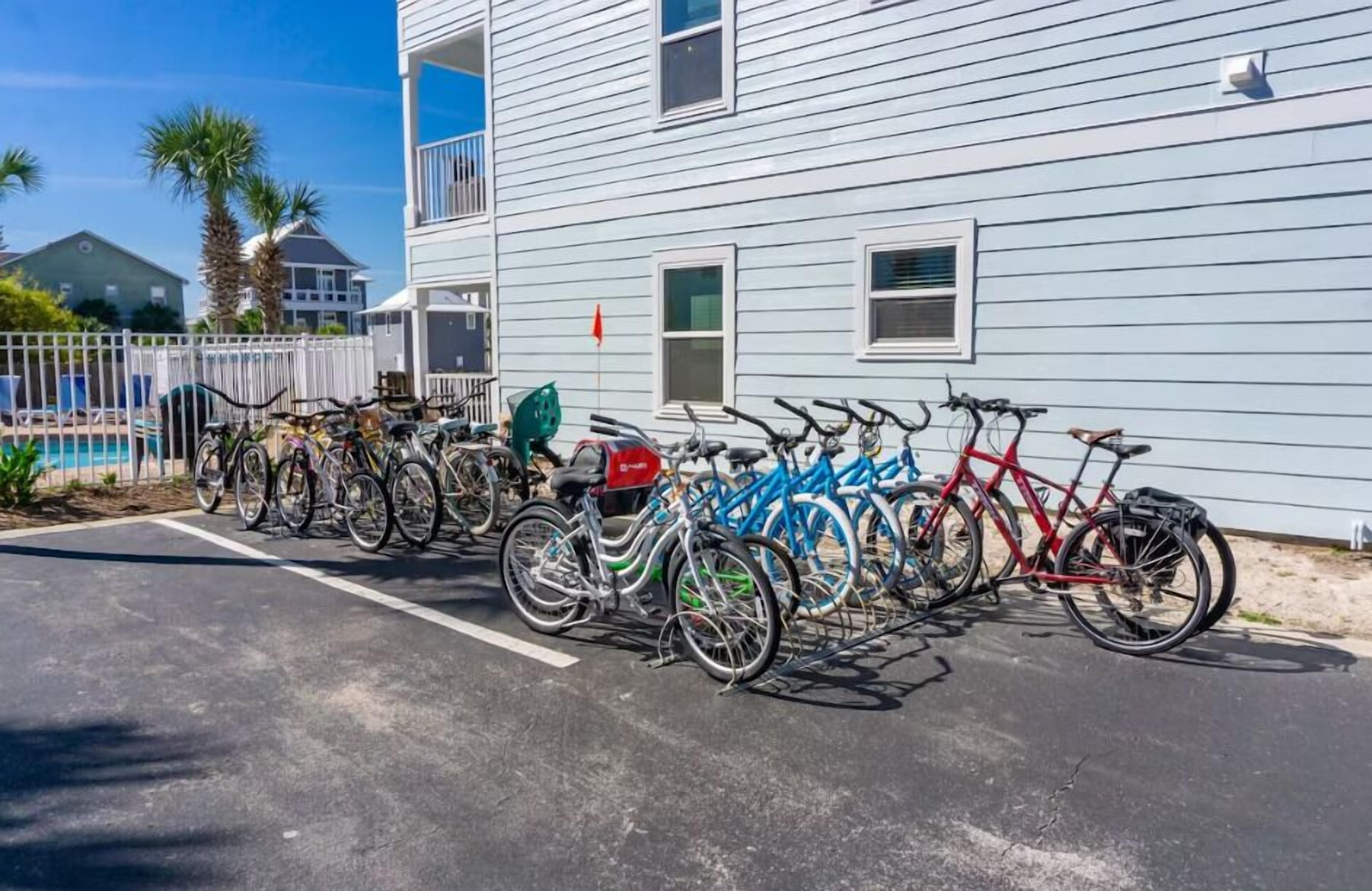Une rangée de vélos est garée devant un bâtiment, avec une piscine en arrière-plan.