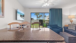 A modern kitchen with granite countertops, wooden chairs, and a ceiling fan. - 🐾️Pet Friendly ~ Beach View - Pool ~ Blue Surf 16A☀️ (Miramar Beach)