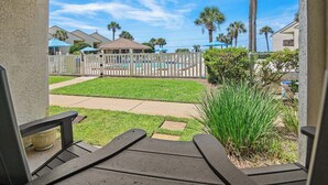 A patio with a view of a backyard, including a pool, palm trees, and a fenced area. - 🐾️Pet Friendly ~ Beach View - Pool ~ Blue Surf 16A☀️ (Miramar Beach)