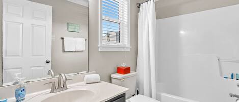 A bathroom with a white sink, a toilet, and a shower area.