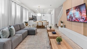 A modern living room with a grey sectional sofa, wooden coffee table, and a TV mounted on the wall.