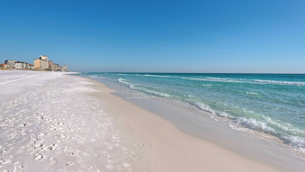 A beach with footprints leading to a building complex.