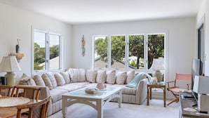 A spacious living room with a large sofa, a coffee table, and a dining area with chairs.