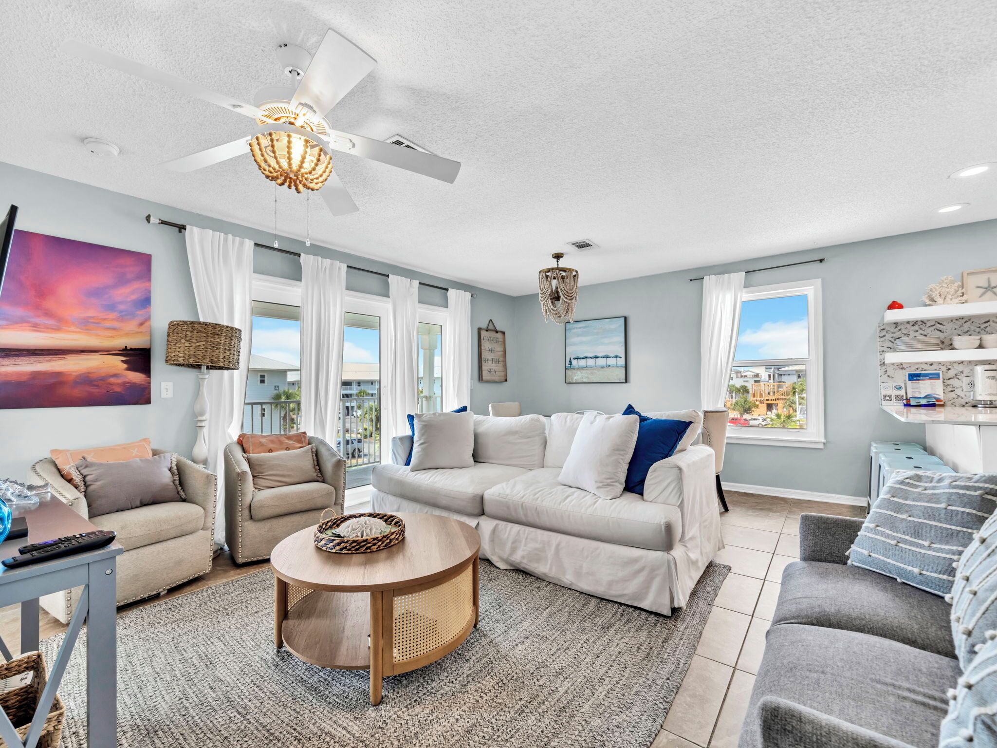 A spacious living room with a large window, a ceiling fan, and a round coffee table.