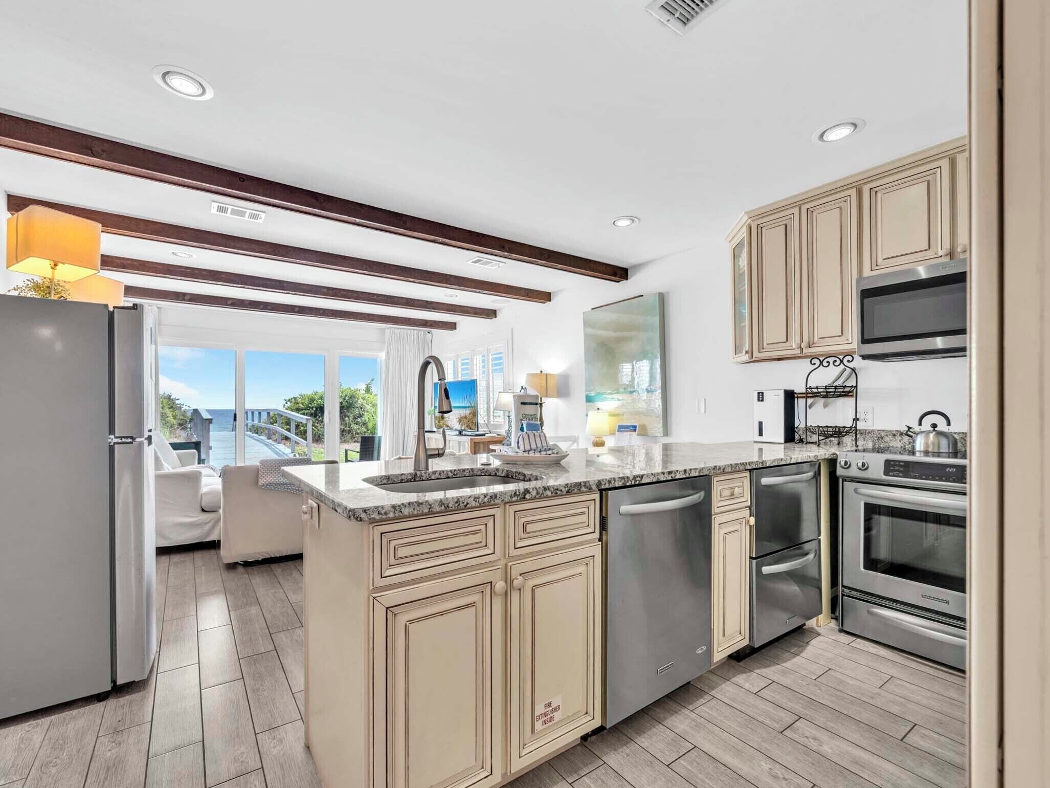 A modern kitchen with a large island, stainless steel appliances, and a view to the outside.