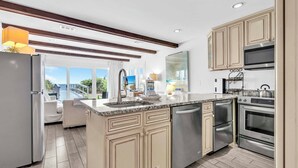 Cocina moderna con una isla grande, electrodomésticos de acero inoxidable y vistas al exterior.