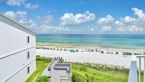 Une vue sur la plage depuis un immeuble doté d’une terrasse et d’une façade blanche.