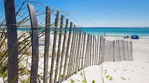 A beach with a wooden fence, a tent, and a clear blue sky.