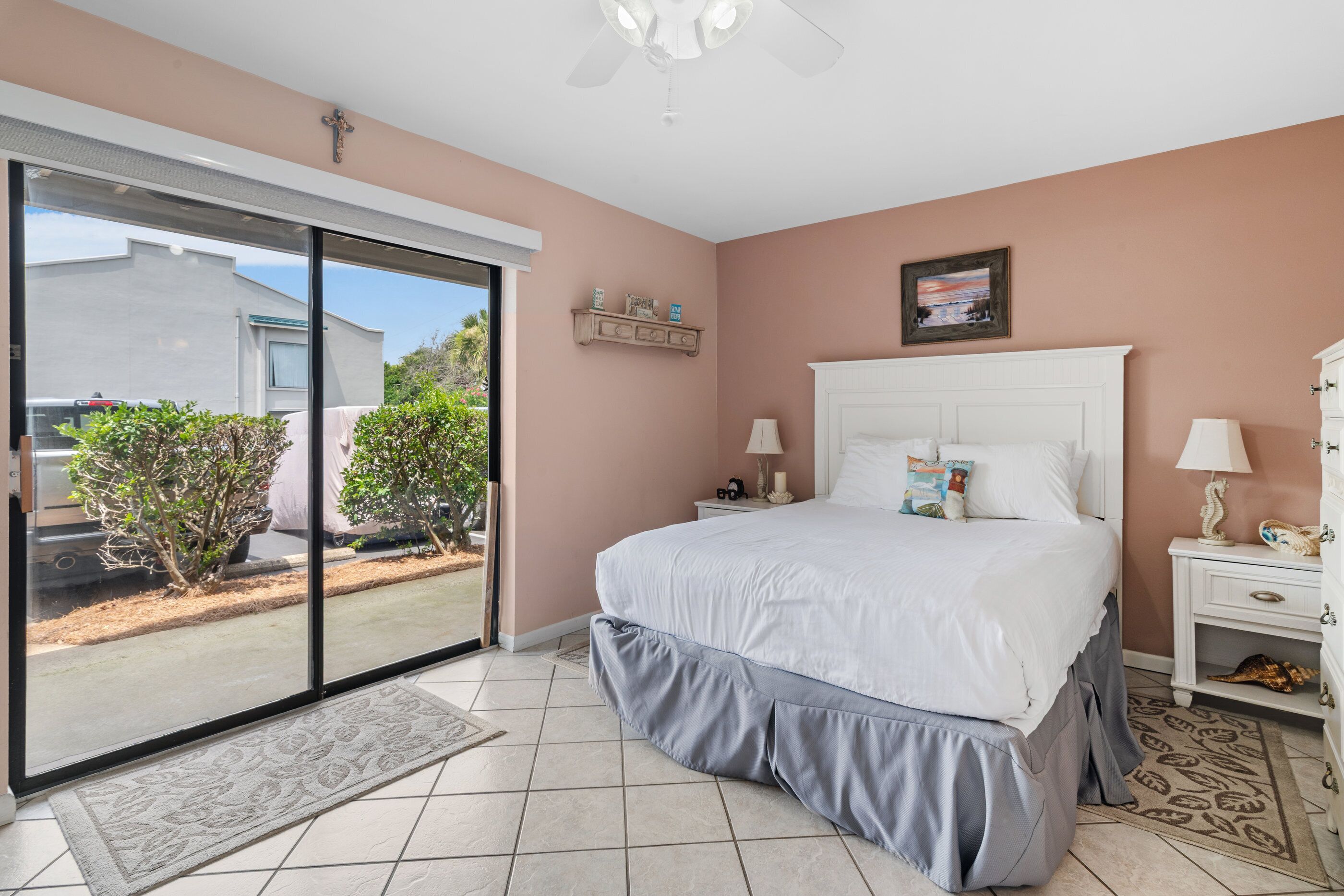 A bedroom with a large bed, a nightstand, a dresser, and a sliding glass door leading to a patio.