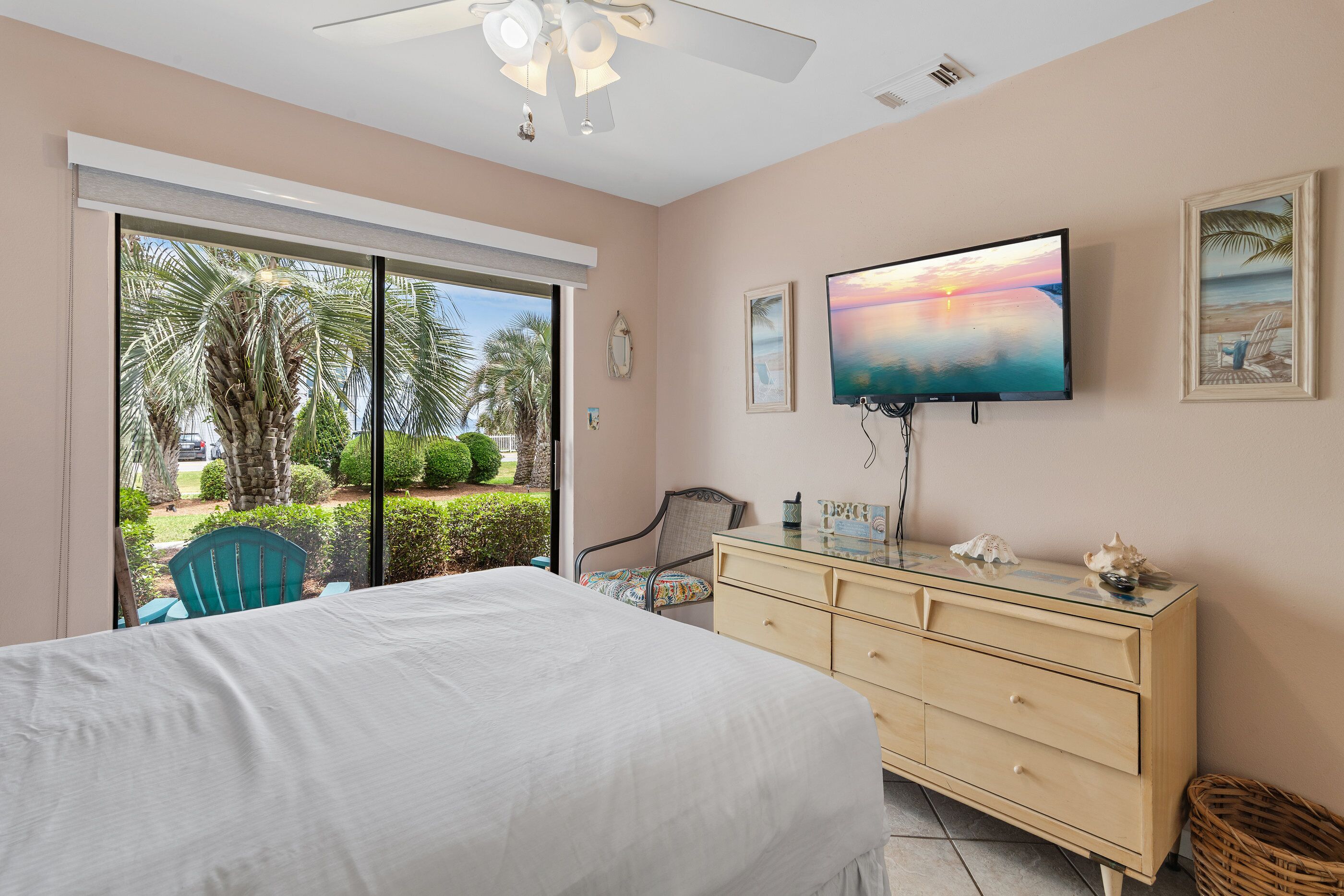 A bedroom with a bed, a dresser, a TV, and a view of the outdoors.