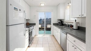 Una cocina moderna con gabinetes blancos, una encimera negra y un tragaluz.
