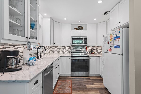 A modern kitchen with white cabinets, a stainless steel oven, a microwave, and a refrigerator.