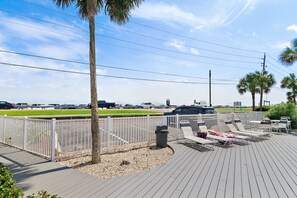 A deck with sun loungers and a trash can, surrounded by a white fence and palm trees. - ⭐Across St from Beach Access-FAB Gulf Views-Pool+Hot Tub-Summer Breeze 103⭐ (Miramar Beach)