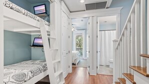 Un dormitorio con literas, un escritorio con computadora y una escalera.