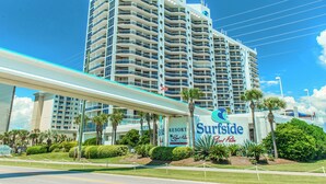 A high-rise hotel with a prominent 'Surfside' sign, multiple balconies, and a well-maintained garden area.