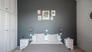 Ein Schlafzimmer mit einem Bett, zwei Nachttischen, einem Kleiderschrank und Wandbildern.