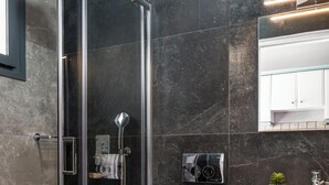 Ein modernes Badezimmer mit einer gläsernen Dusche, einer weißen Toilette und einem Waschbecken mit Spiegel darüber.