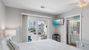 Hotelkamer met een groot bed, een televisie, een balkon met uitzicht op gebouwen en een badkamer met spiegel en wastafel.