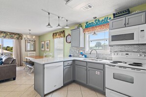 A modern kitchen with a built-in island, white appliances, and a clock on the wall.