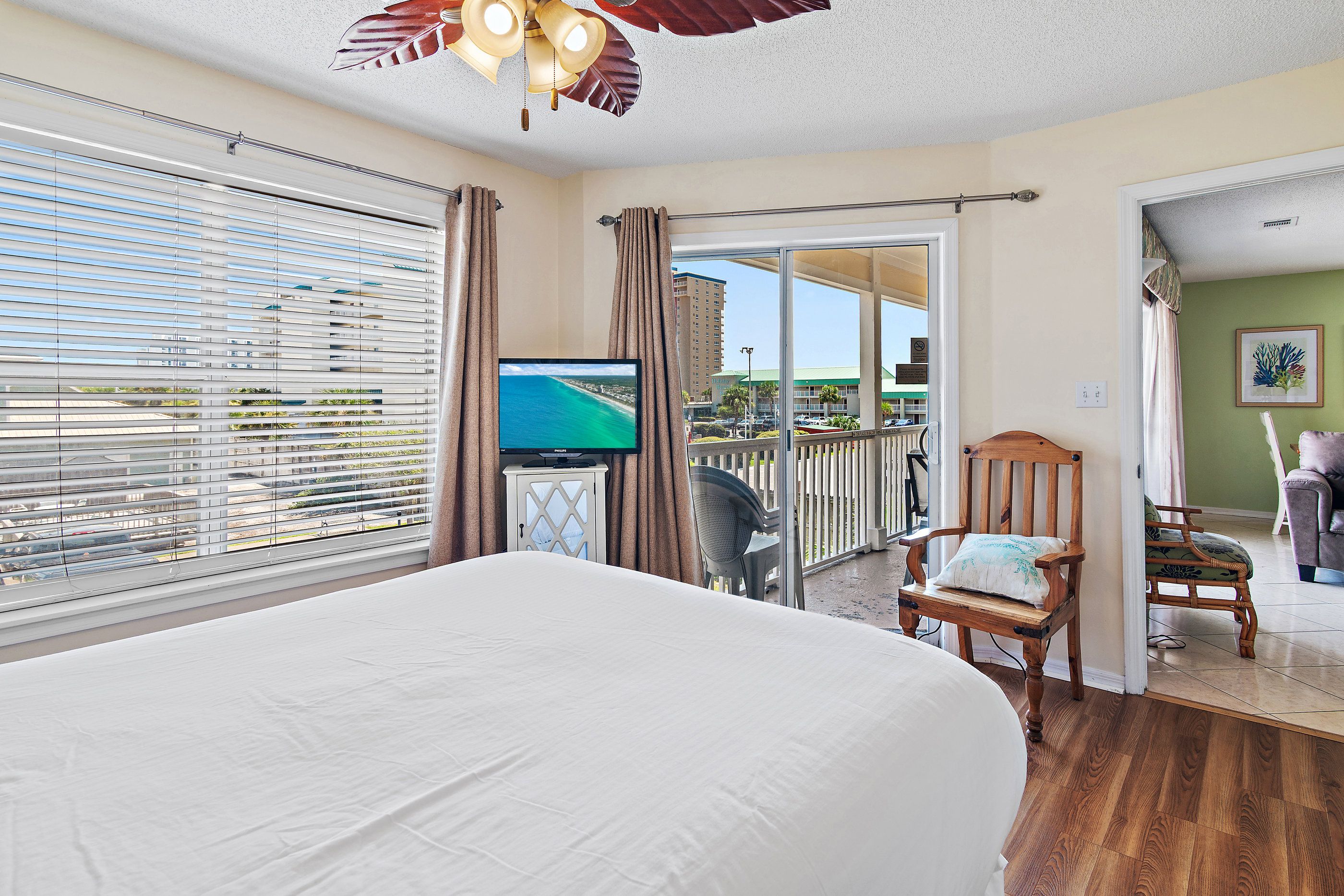 A hotel room with a bed, a television, a chair, and a view of the outside.
