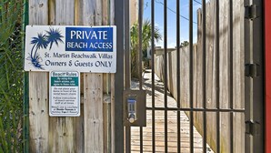 A gated entrance to a private beach area with a sign indicating beach access is for owners and guests only.