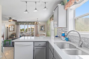 A modern kitchen with a large island, stainless steel appliances, and a view of the city through the window. - 🌞Private Path to Beach~3BR St Martin Beachwalk Villas 221 (Destin)