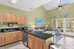 A kitchen with wooden cabinets, a black countertop, and a ceiling fan. - ☀Across From Beach~Community Pool~ Hot Tub~Caribbean Dunes 203☀ (Destin)