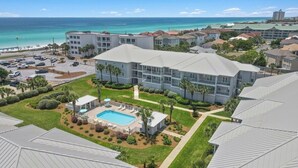 A hotel with a swimming pool, multiple buildings, and a view of the ocean.