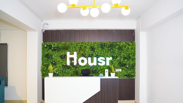 A reception desk with a green wall and the word "Housr" on it. - Housr 78 Madhapur Hyderabad Hitech City (Hyderabad)